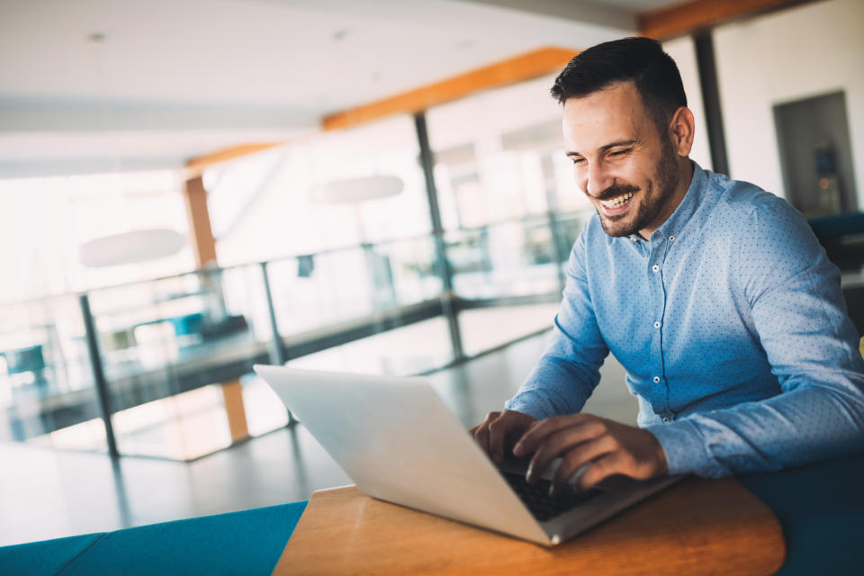 Man using laptop computer and smiling.