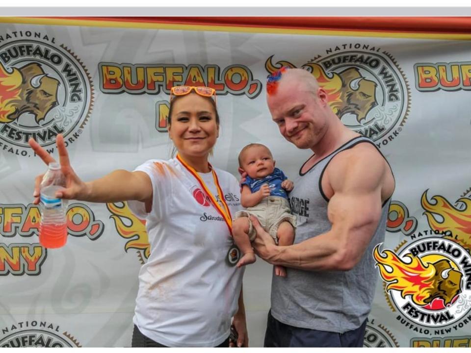 Competitive eater Miki Sudo and her husband, Nick Wehry, pose with their newborn, Max, at the 2021 National Buffalo Wing Eating Championship.