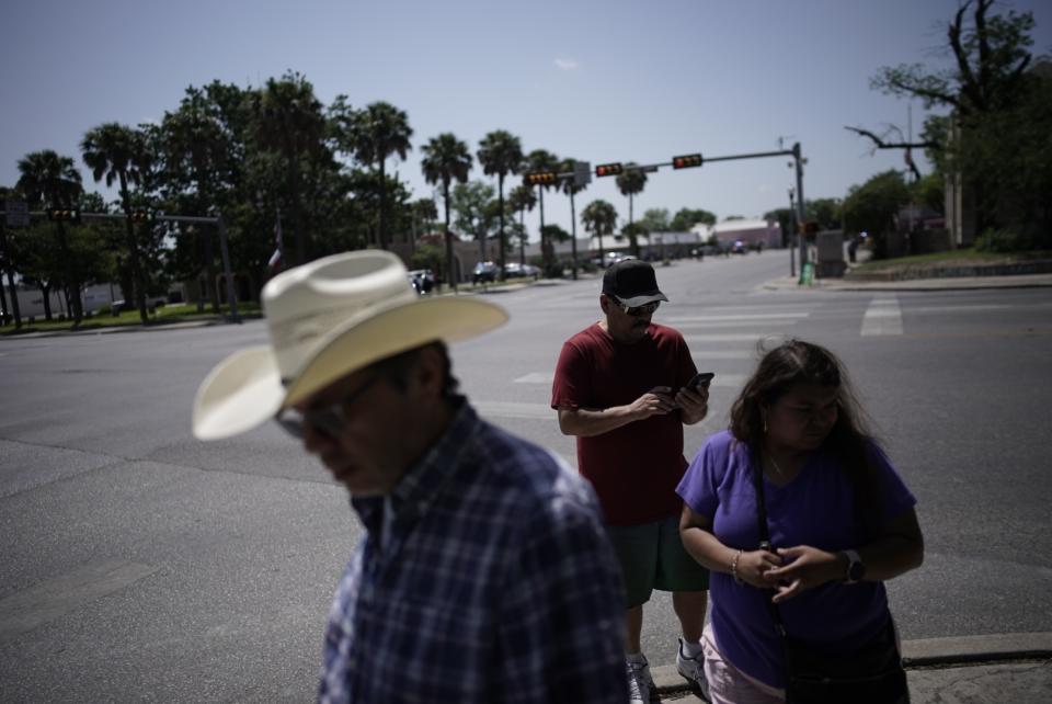 People make their way toward a memorial site set up for victims of the mass shooting at Robb Elementary School in Uvalde, Texas, Sunday, May 29, 2022. In a town as small as Uvalde, even those who didn't lose their own child lost someone. Some say now that closeness is both their blessing and their curse: they can lean on each other to grieve. But every single one of them is grieving. (AP Photo/Wong Maye-E)