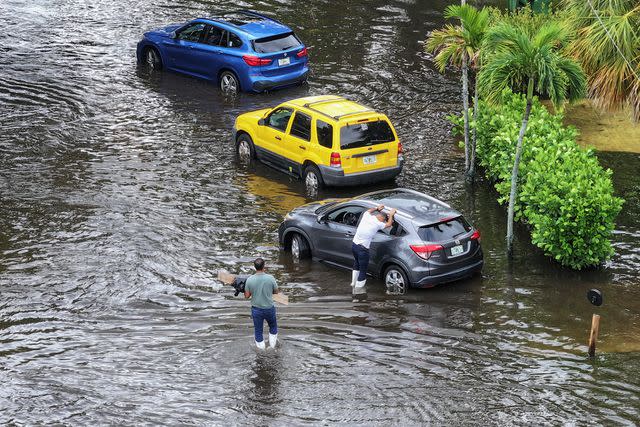 <p>Joe Raedle/Getty</p> Cars standing floodwaters in South Florida on June 13, 2024