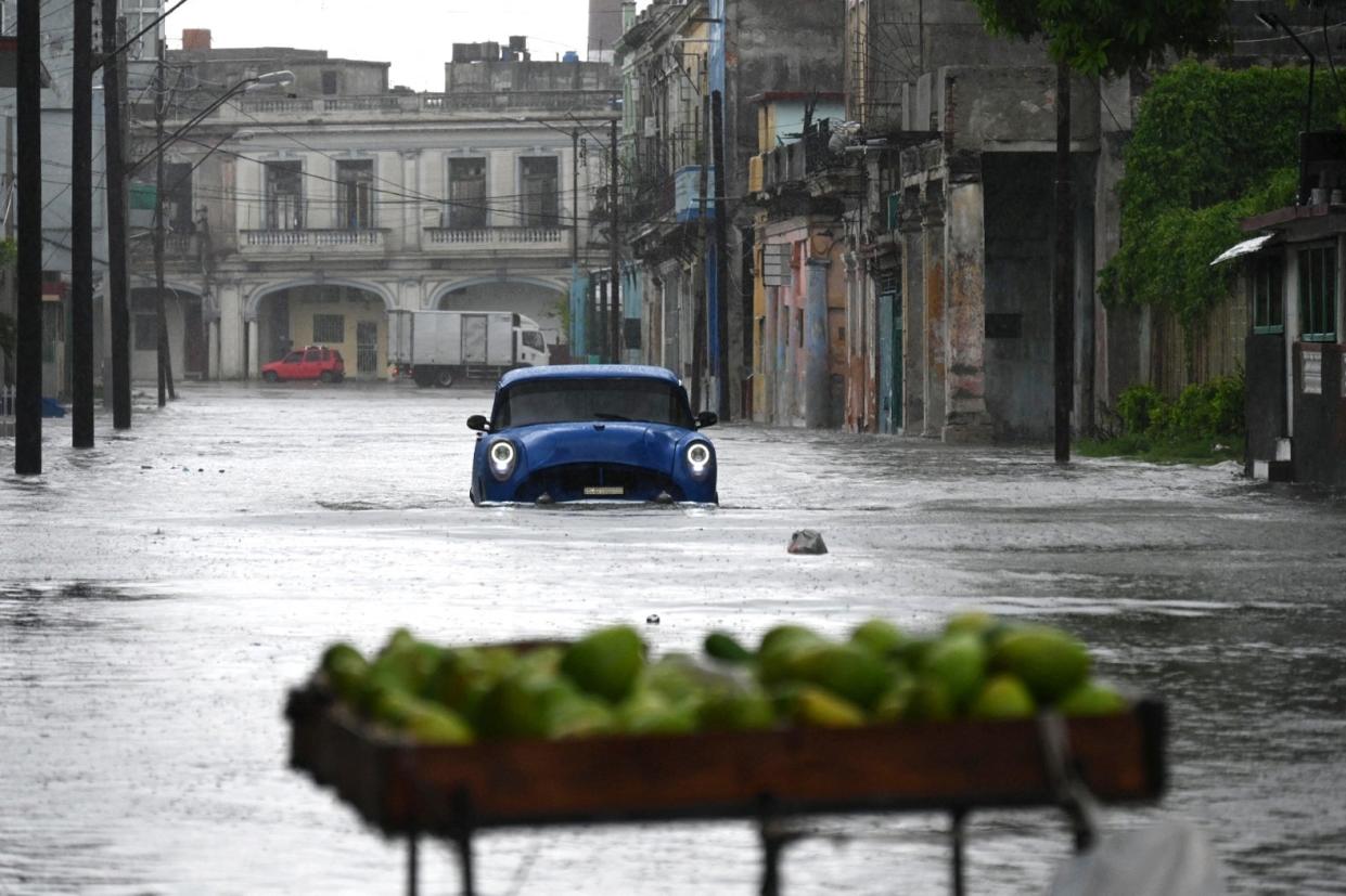 An old American car drives through a flooded street in Havana, on August 29, 2023, during the passage of tropical storm Idalia. Tropical Storm Idalia strengthened into a hurricane this Tuesday and forecasters are forecasting it to become 