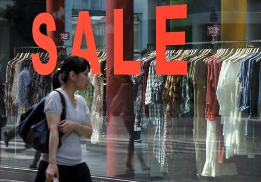 A pedestrian walks in front of a boutique advertising a sale in Tokyo's Shinjuku shopping district, 2010. A bill to double Japan's sales tax and partially plug its gaping debt hole cleared its final parliamentary hurdle in a triumph for the prime minister that could ultimately also cost him his job