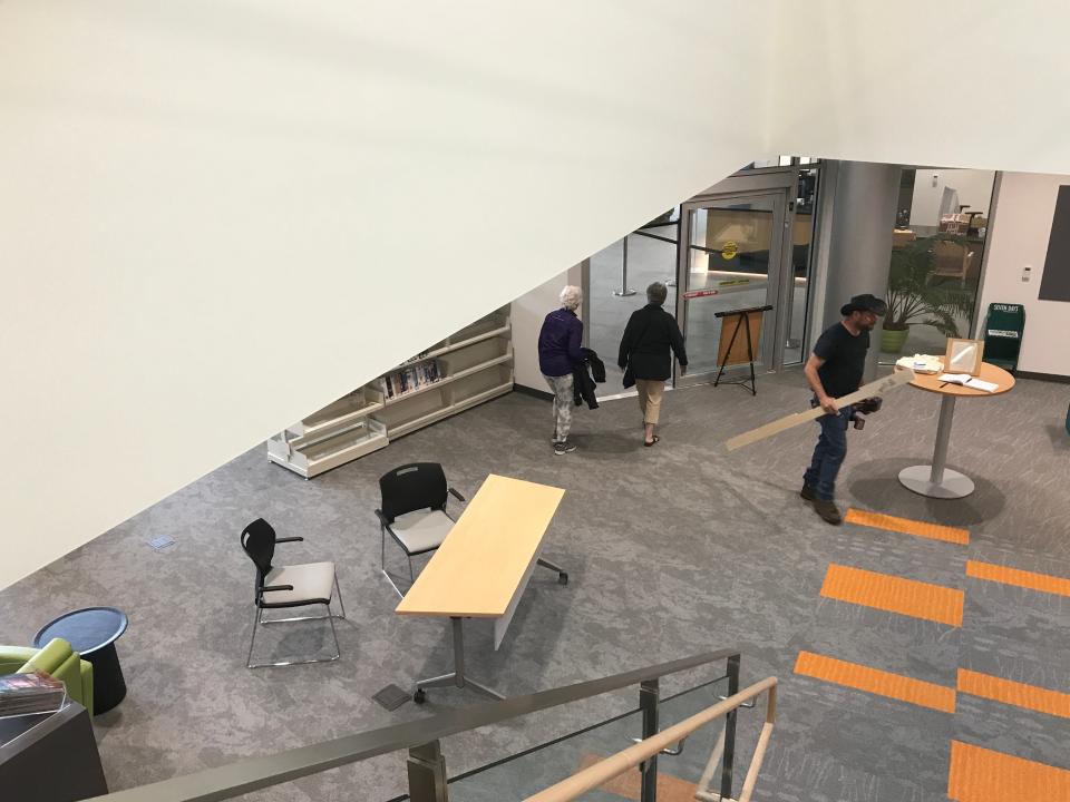 Sonny Cassani, left, and Pam MacPherson exit South Burlington's new Public Library on Market Street, while carpenter Keith Mocheda (with hat) prepares to head upstairs to install some trim on  July 21, 2021.
This view is from the building's central stairwell.