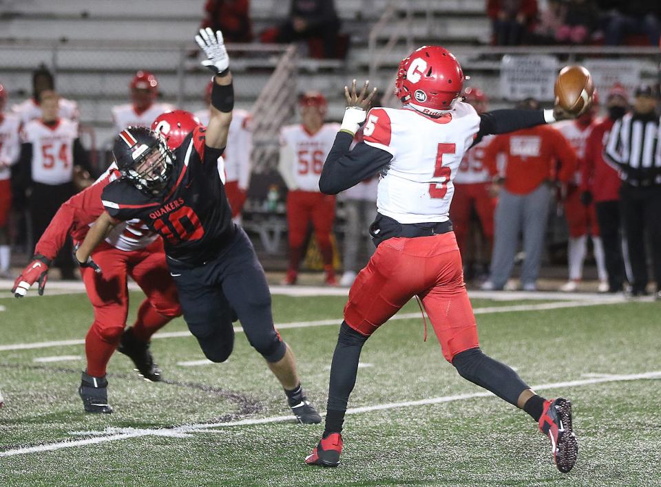 New Philadelphia’s Mitchell Stokey pressures Youngstown Chaney quarterback Jason Hewlett in the first quarter of the Division III Regional second round game Friday.