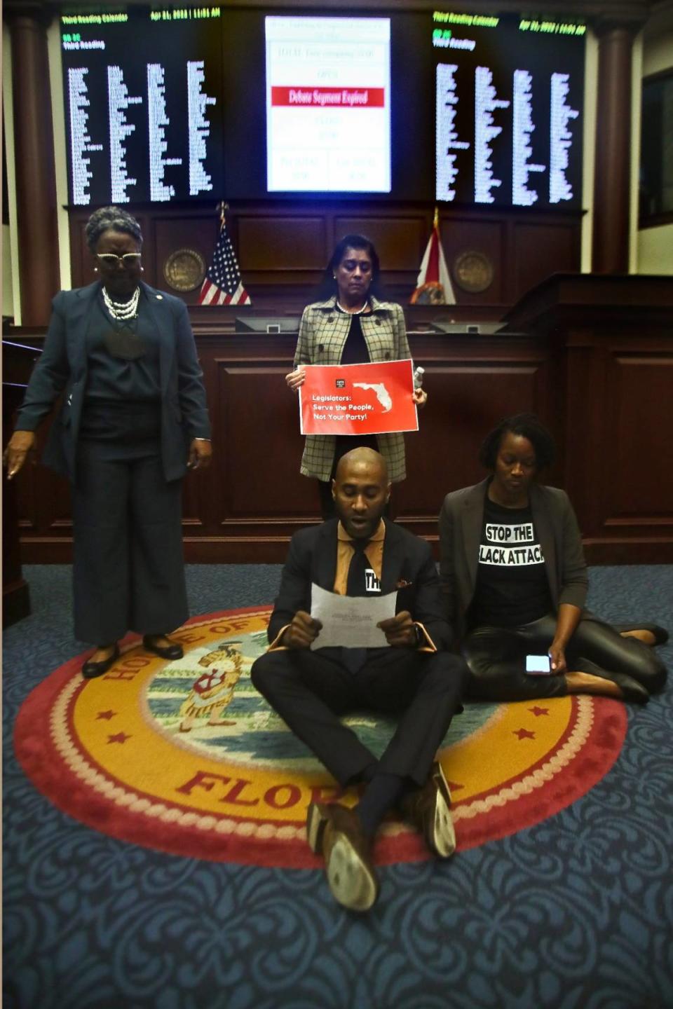 Rep. Yvonne Hayes Hinson, D-Gainesville, Rep. Daisy Morales, D-Orlando, Rep. Tray McCurdy, D-Orlando (in front) and Rep. Angie Nixon, D-Jacksonville, protest on the Florida Seal as debate is halted in the House of Representatives Thursday, April 21, 2022, at the Capitol in Tallahassee, Fla. The session was halted by the protest, but continued after a brief recess.