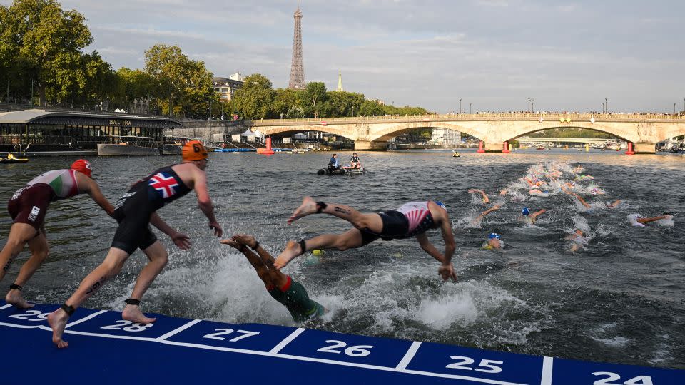 Triathlon athletes dive in the Seine river during the men's 2023 World Triathlon Olympic Games test event in Paris on August 18, 2023. - Bertrand Guay/AFP/Getty Images