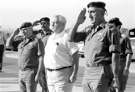 Israeli Defence Minister Ariel Sharon (C) stands at attention during a visit to the central command military base in this picture taken October 30, 1981 and released by Israel's Defence Ministry. REUTERS/Israeli Defence Ministry/Handout/Files