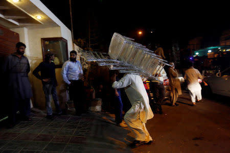 A worker carries in chairs as relatives gather outside the residence of Junaid Jamshed, pop star turned evangelical Muslim cleric, in Karachi, Pakistan December 7, 2016. REUTERS/Akhtar Soomro