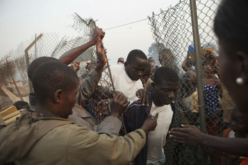 People who had been sleeping in a food distribution area push their way back in, as they are ordered to move to a new settlement area, in an informal camp housing an estimated 100,000 displaced people, at Mpoko Airport in Bangui, Central African Republic, Wednesday, Jan. 8, 2014. Food and supplies distribution by the World Food Program and the United Nations Refugee Agency began Tuesday and was expected to last 10 days. (AP Photo/Rebecca Blackwell)