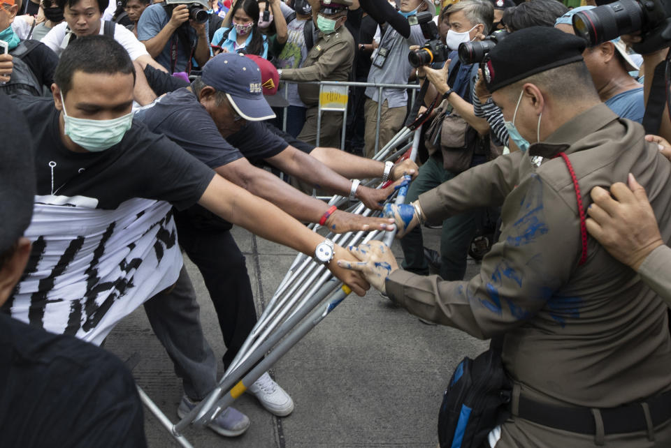 Anti-government protesters push a metal barrier into inside of the Samranrat police station in Bangkok, Thailand, Friday, Aug, 28, 2020. The protesters tussled with police on Friday as 15 of their movement leaders turned up at a police station to answer a summons linked to demonstrations denouncing the arrests. (AP Photo/Sakchai Lalit)