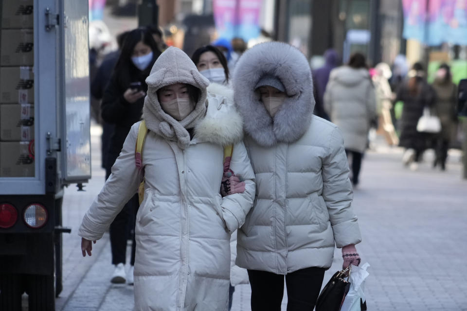 Women walk on the street during frigid weather condition in Seoul, South Korea, Wednesday, Jan. 25, 2023. Thousands of travelers swarmed a small airport in South Korea's Jeju island on Wednesday in a scramble to get on flights following delays by snowstorms as frigid winter weather gripped East Asia for the second straight day. (AP Photo/Ahn Young-joon)