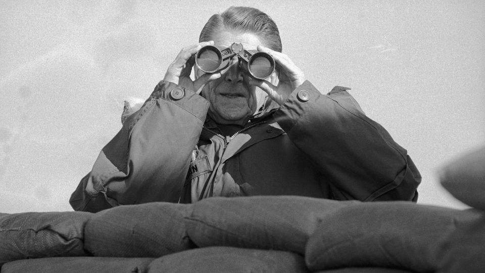 Reagan looks through binoculars to view North Korean positions from the observation deck at Guard Post Collier at the DMZ in 1983. - Bettmann/Getty Images