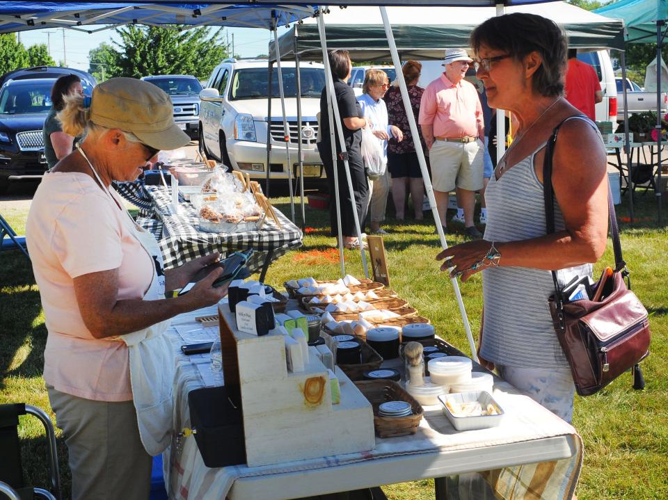 Lori Knapp, right, purchases specialty soap Saturday, June 25, 2022, from Marsha Scoville at the Wik-N-Wax Candle & Bath stand at the Alliance Farmers Market.