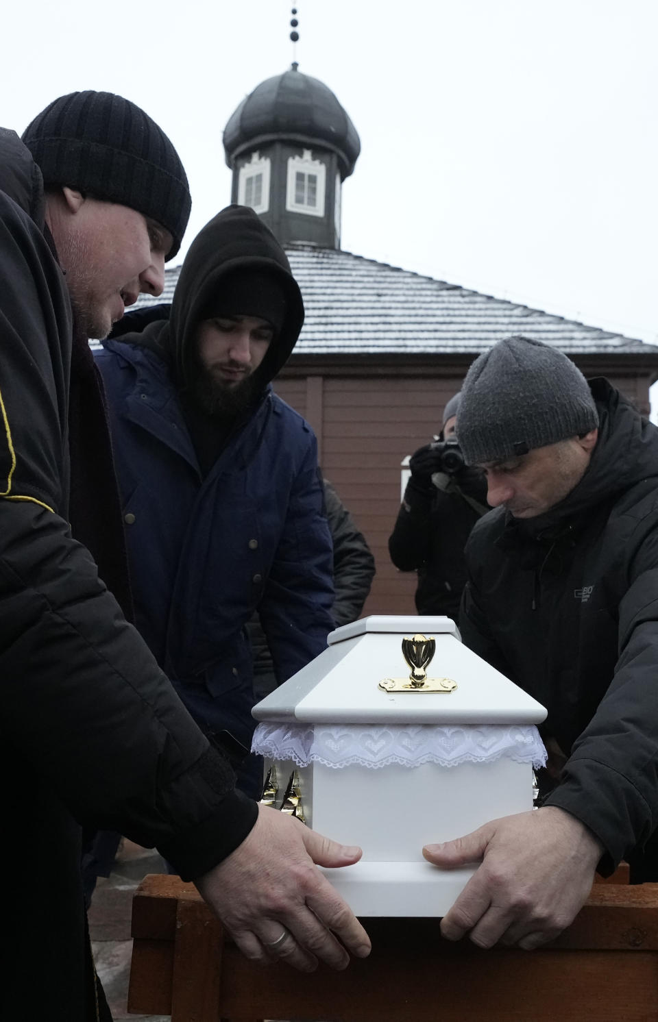 A Polish imam, left, and two other members of a Muslim community bury the tiny white casket of an unborn Iraqi boy, in Bohoniki, Poland, on Tuesday Nov. 23, 2021. The child is the latest life claimed as thousands of migrants from the Middle East have sought to enter the European Union but found their path cut off by a military build-up and fast approaching winter in the forests of Poland and Belarus. (AP Photo/Czarek Sokolowski)