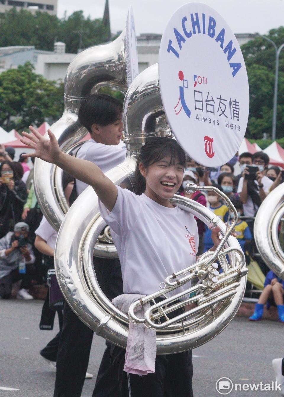 京都橘高校吹奏樂部的一位扛著蘇沙號樂器的學生在進場演出前，開心的向兩邊的觀眾揮手致意。她的蘇沙號上包覆寫有『日台友情 Always Here』字樣顯得非常搶眼。   圖：張良一/攝