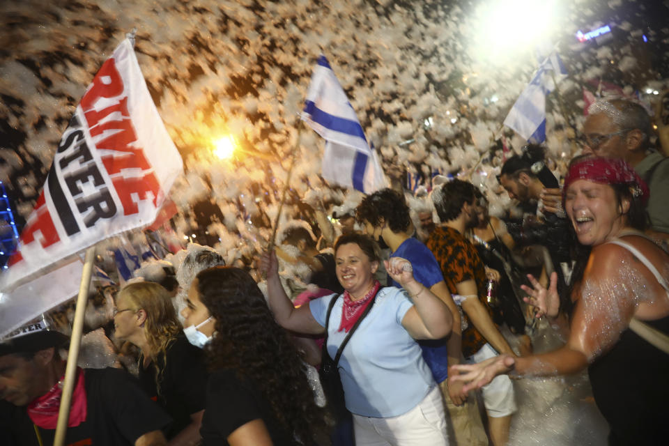 Israelis celebrate the swearing in of the new government in Tel Aviv, Israel, Sunday, June 13, 2021. Israel's parliament has voted in favor of a new coalition government, formally ending Prime Minister Benjamin Netanyahu's historic 12-year rule. Naftali Bennett, a former ally of Netanyahu became the new prime minister. (AP Photo/Oded Balilty)