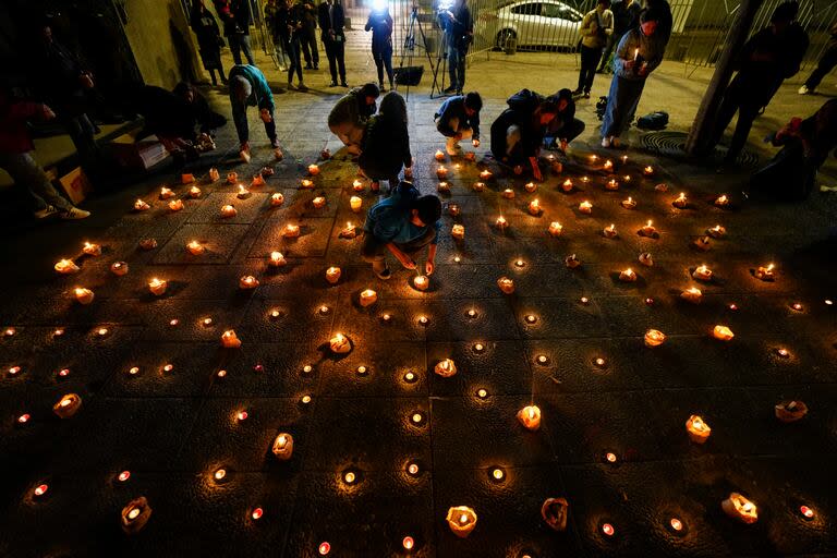 Varias personas encienden velas durante una vigilia frente a la sede de los Carabineros en honor de tres policías asesinados en el sur de Chile