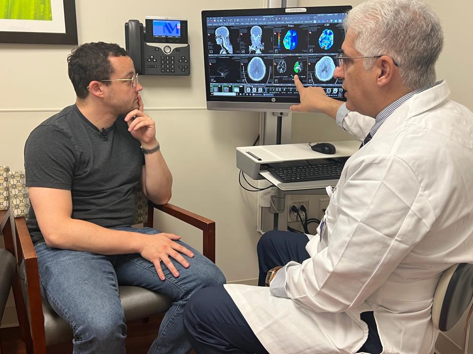 Patient and doctor in a hospital room looking at brain scan images