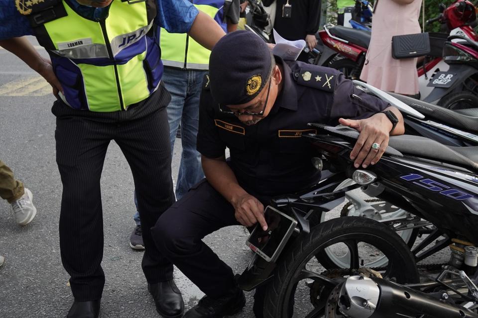 A senior police officer shows the tiny license plate on the bike's rear.