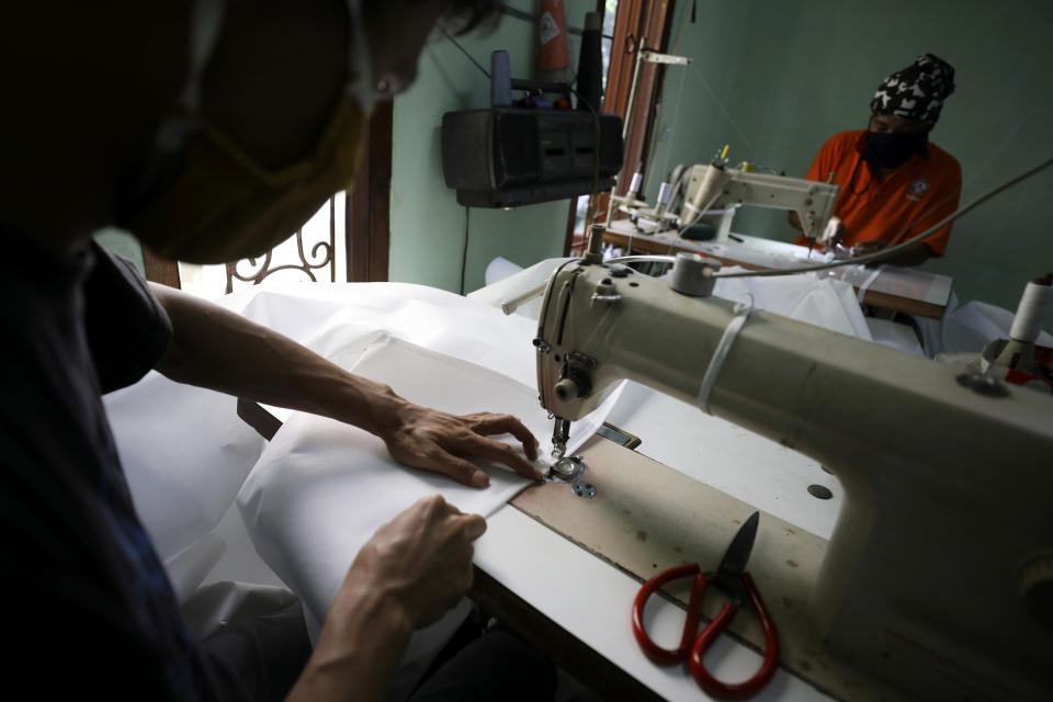 In this Thursday, April 2, 2020, photo, tailors make hazmat suits at a home garment factory in Depok, Indonesia. When an Indonesian businesswoman Maryati Dimursi heard from friends working in hospitals that they don't have enough proper protective gear when dealing with suspected COVID-19 patients, she decided to help them by crowdfunding to produce proper hazmat suits for distribution to various hospitals in the country. (AP Photo/Dita Alangkara)