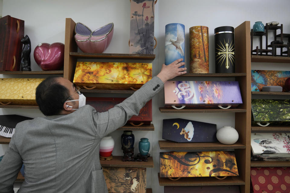 Wilson Tong, CEO of LifeArt Asia takes the models of paper coffins at the factory of LifeArt in Hong Kong, Friday, March 18, 2022. Hong Kong is running short of coffins during its deadliest outbreak of the coronavirus pandemic. LifeArt, a company in Hong Kong is trying to make an alternative, cardboard coffin, which it says is environmentally-friendly. (AP Photo/Kin Cheung)