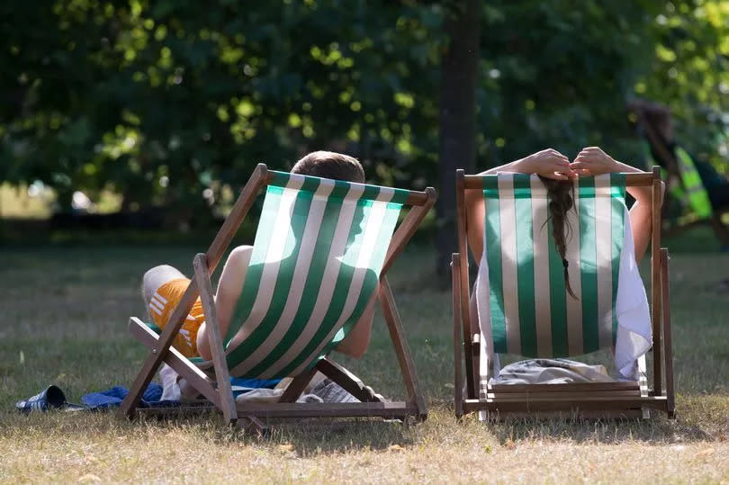 A couple relax on deckchairs in the warm weather in Hyde Park