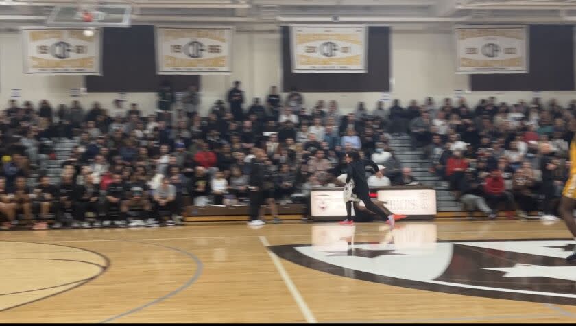 Sierra Canyon High's 12-year-old equipment manager Eric Ginsburg speeds off the court after mop-up duty at Crespi High.
