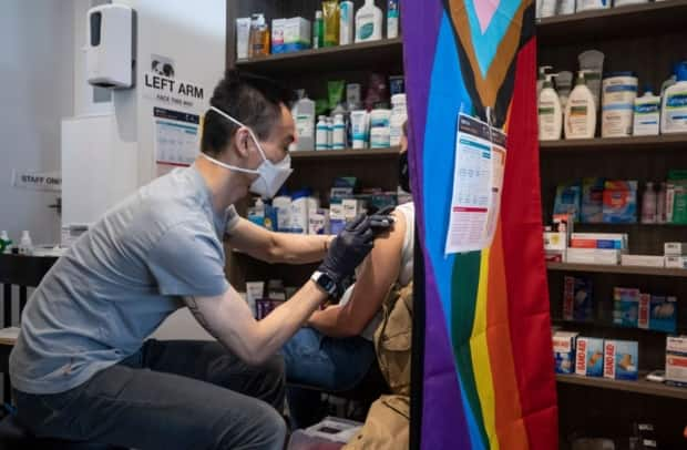 Pharmacist Eugene Woo delivers an AstraZeneca-Oxford vaccine at Davie Pharmacy in Vancouver, B.C. on Tuesday. (Ben Nelms/CBC - image credit)