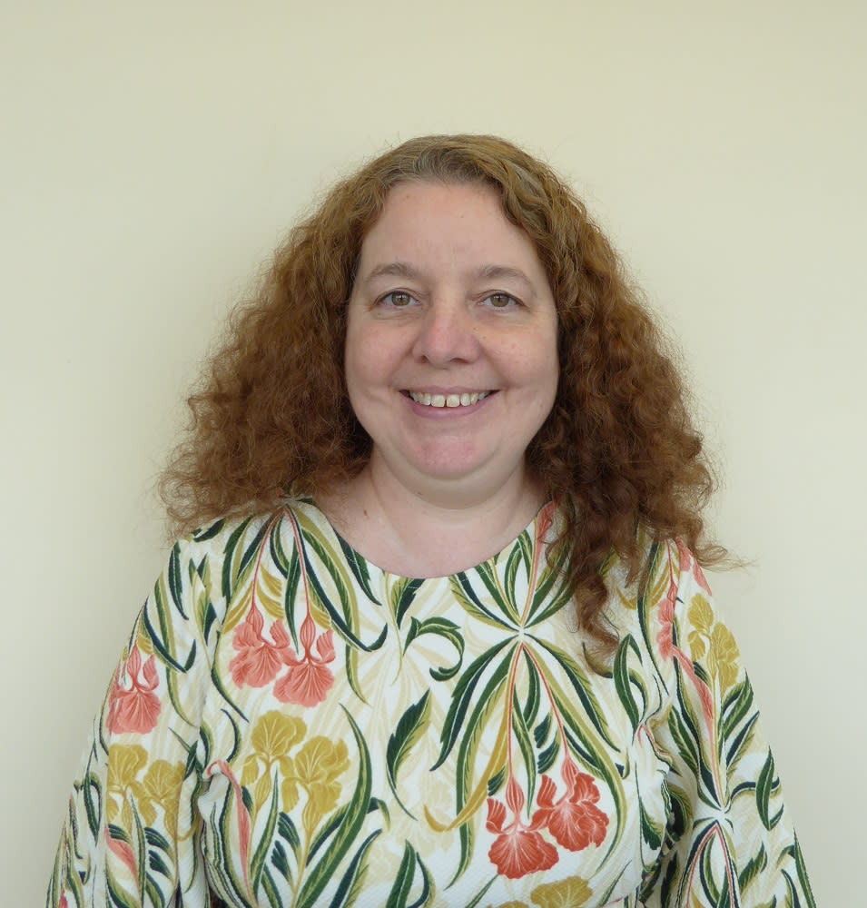 Caroline O'Connor smiling and wearing a floral top