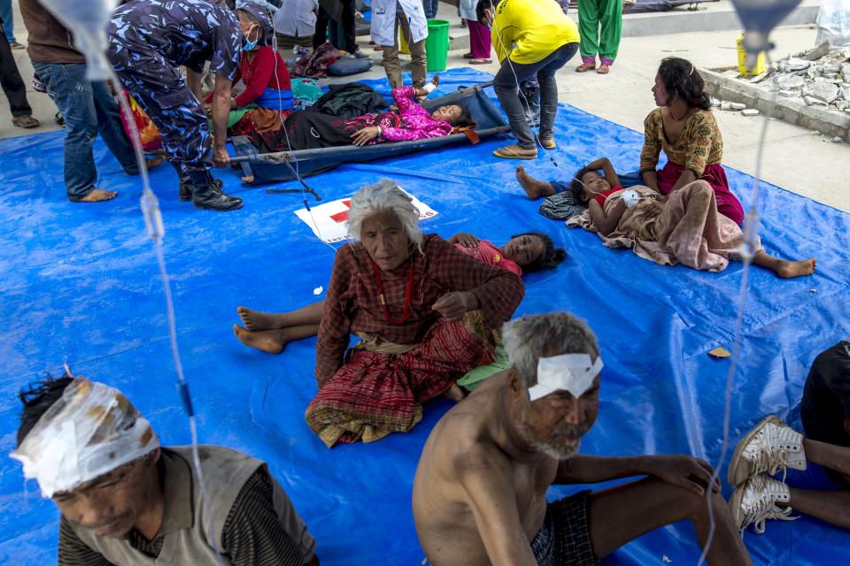 Earthquake victims sit on a tarpaulin as they receive medical treatment outside Dhading hospital in Dhading Besi, Nepal