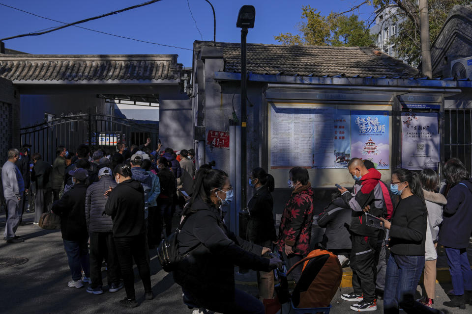 Residents wearing face masks to help curb the spread of the coronavirus line up to receive booster shots against COVID-19 at a vaccination site with a billboard displaying a propaganda poster supporting the Beijing 2022 Winter Olympic Games, near a residential area in Beijing, Friday, Oct. 22, 2021. China's capital Beijing has begun offering booster shots against COVID-19, four months before the city and surrounding regions are to host the Winter Olympics. (AP Photo/Andy Wong)