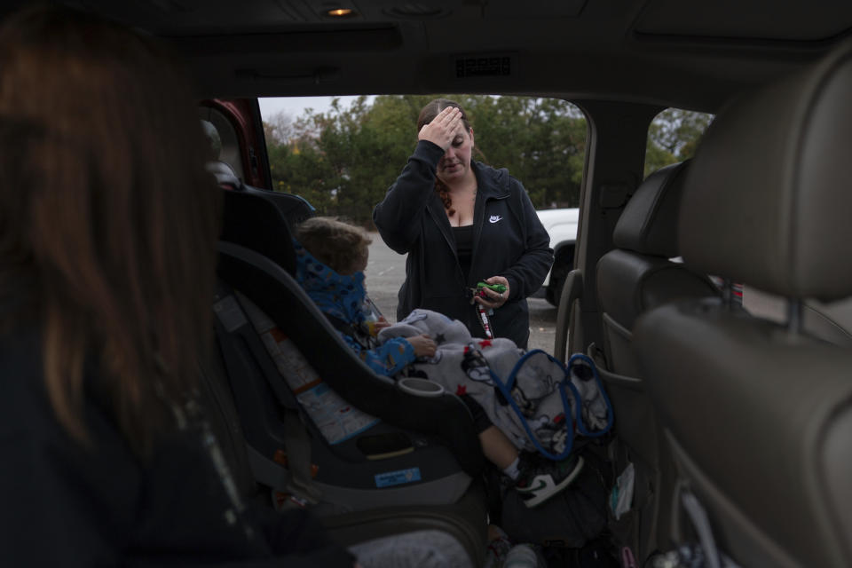 Jesse Johnson pauses before closing the van door after shopping for Halloween costumes with her children at Spirit Halloween in Findlay, Ohio, Friday, Oct. 20, 2023. Earlier this year, Johnson started a job with the Family Resource Center, the same organization that employed the peer support worker who was so instrumental in her own early recovery. (AP Photo/Carolyn Kaster)