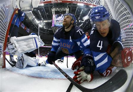 Finland's Leo Komarov (71) looks on as Finland's Ossi Vaananen (4) falls on Russia's Alexander Radulov (bottom, R) inside the Finland goal during the third period of their men's quarter-finals ice hockey game at the Sochi 2014 Winter Olympic Games February 19, 2014. REUTERS/Julio Cortez/Pool