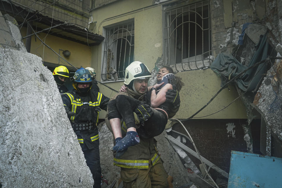 In this photo released by State Emergency Service of Ukraine on Monday, Jan. 16, 2022, a Ukrainian State Emergency Service firefighter carries a wounded woman out of the rubble from a building after a Russian rocket attack on Saturday in Dnipro, Ukraine, Sunday, Jan. 15, 2023. (Pavel Petrov, SESU via AP)