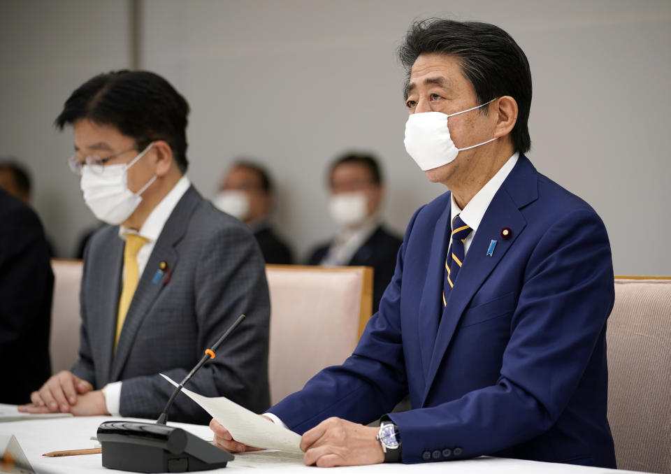 Japanese Prime Minister Shinzo Abe, right, declares a state of emergency during a meeting of the task force against the coronavirus at the his official residence in Tokyo, Tuesday, April 7, 2020. Abe declared a state of emergency for Tokyo and six other prefectures to ramp up defenses against the spread of the coronavirus. (Franck Robichon/Pool Photo via AP)