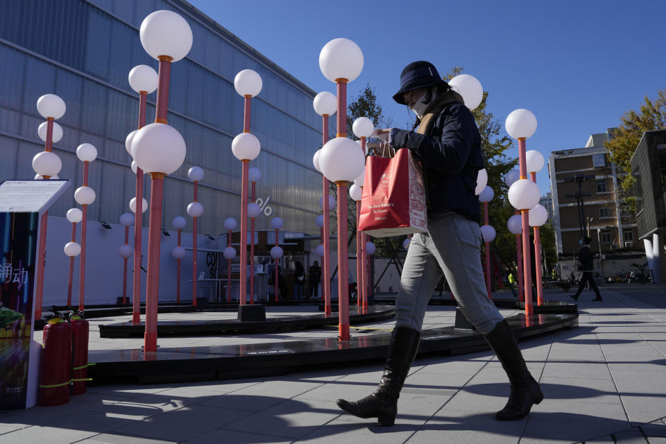 A shopper walks through a mall district in Beijing, Saturday, Nov. 11, 2023. Shoppers in China have been tightening their purse strings, raising questions over how faltering consumer confidence may affect the annual Singles' Day online retail extravaganza. (AP Photo/Ng Han Guan)