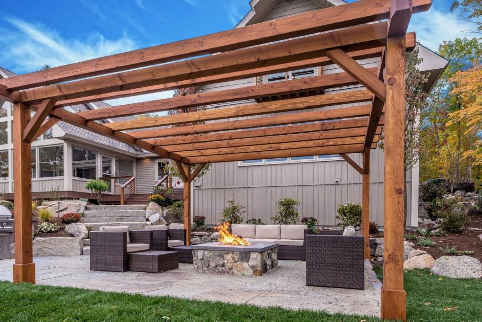 Fire pit under a patio pergola, surrounded by modern patio furniture