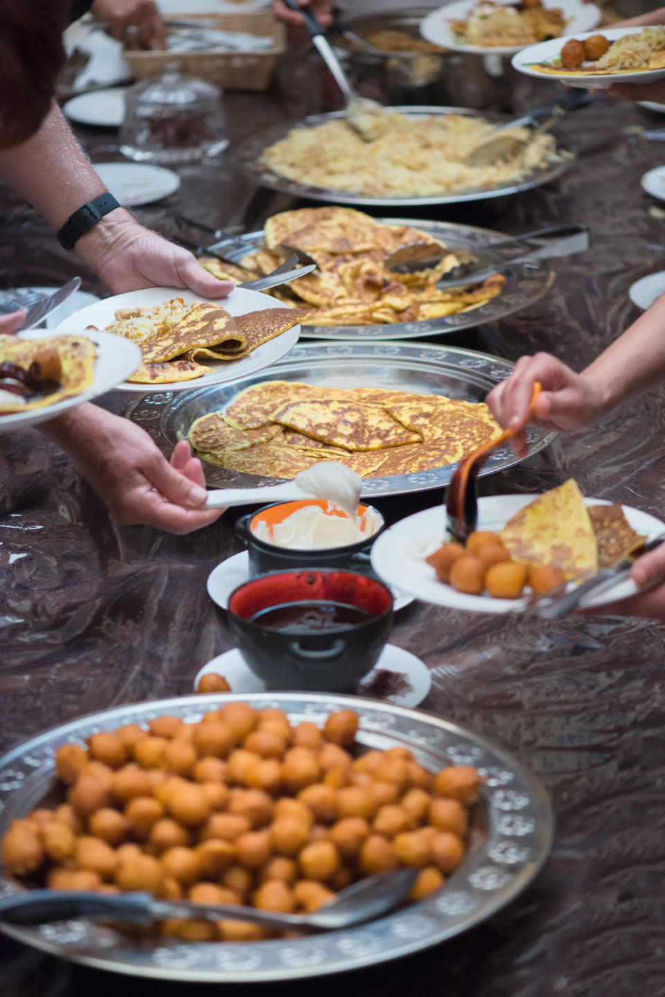 People serve themselves a variety of dishes at a buffet table, including rice and fried round snacks