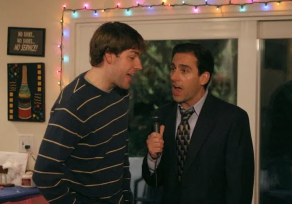 Two characters from "The Office" during a party scene, one holding a microphone