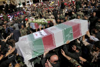 Mourners carry flag-draped caskets during a mass funeral for victims of Saturday's terror attack on a military parade, in the southwestern city of Ahvaz, Iran, Monday, Sept. 24, 2018. Thousands of mourners gathered at the Sarallah Mosque on Ahvaz's Taleghani junction, carrying caskets in the sweltering heat. (AP Photo/Ebrahim Noroozi)