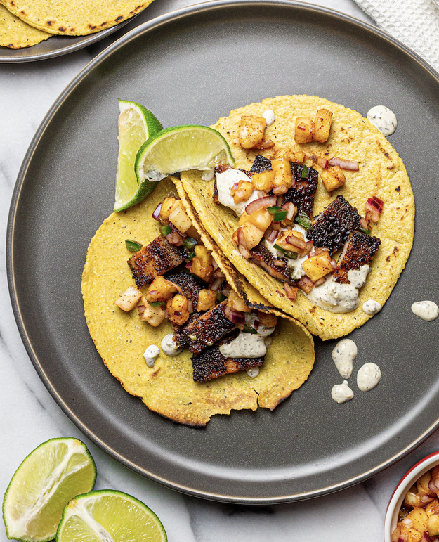 Bacon tacos on a plate on top of corn tortillas with lime, pineapple salsa.