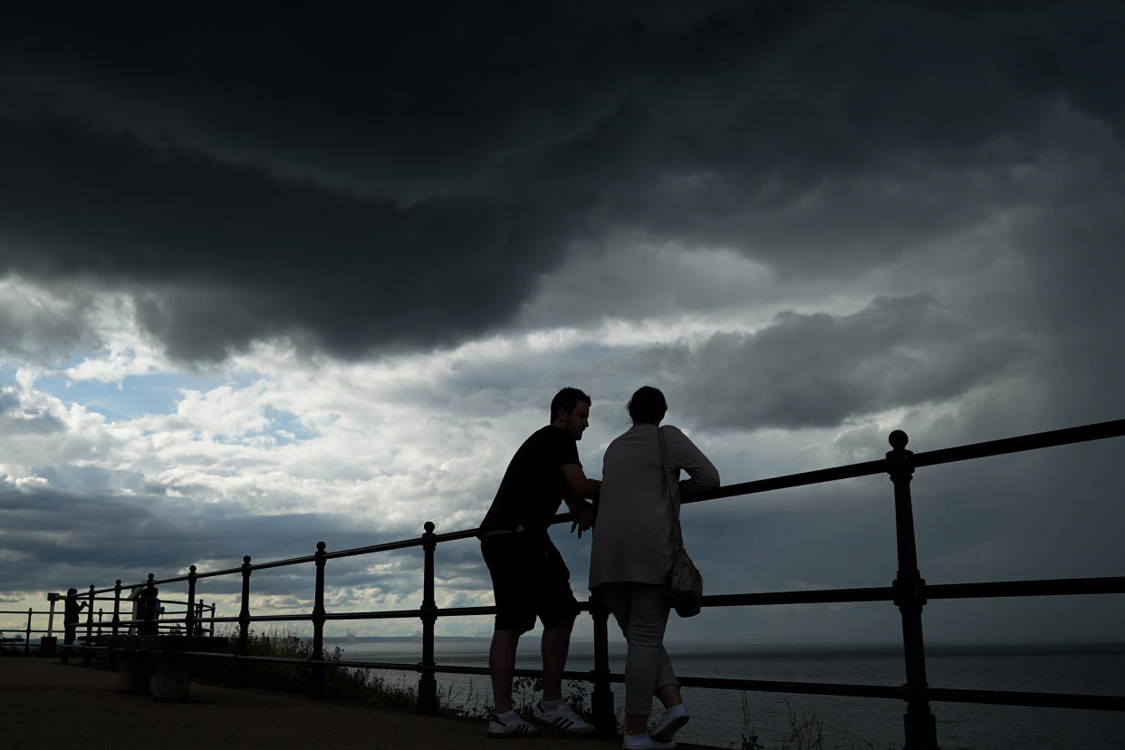 SALTBURN BY THE SEA, ENGLAND - AUGUST 02: A couple stand on the upper promenade as thunder clouds pass overhead on August 02, 2020 in Saltburn By The Sea, England. Heavy showers have continued through much of the day but will eventually give way to clearer skies into the evening. (Photo by Ian Forsyth/Getty Images)