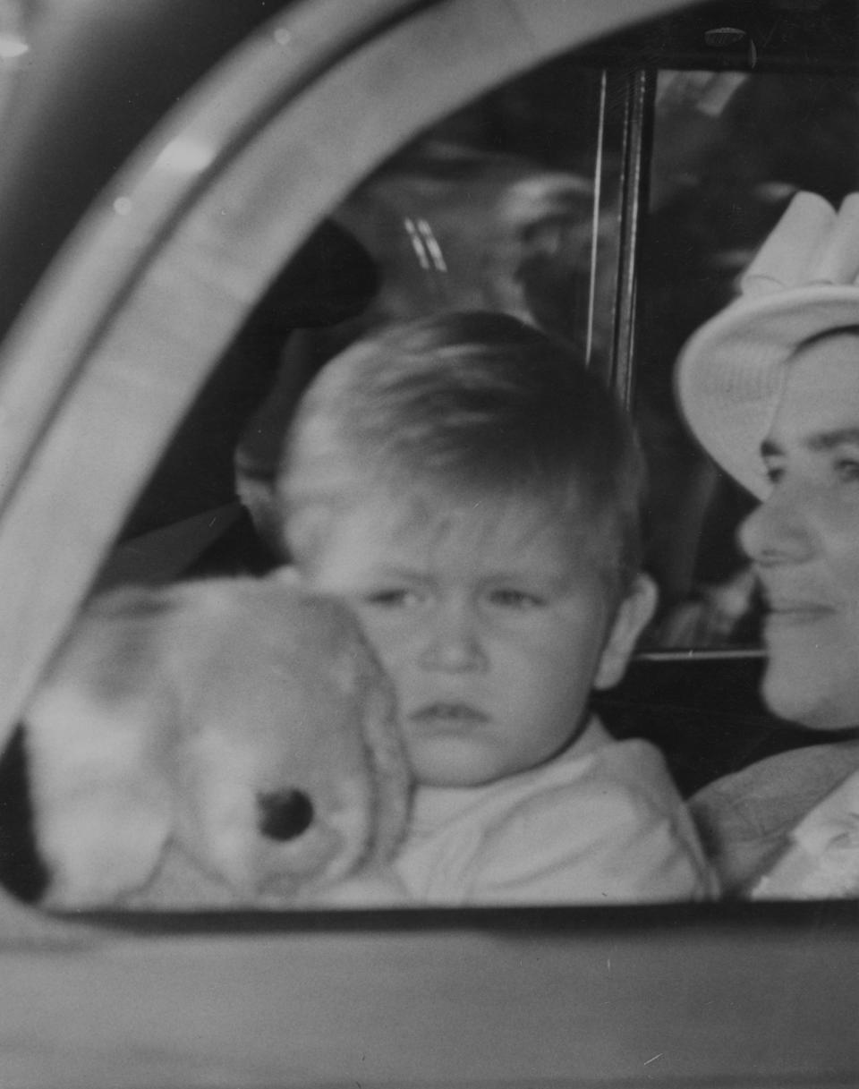 <p>A two-year-old Prince Charles, clutching his puppy teddy, is taken for a drive from Clarence House in August 1950 [Photo: PA Images] </p>