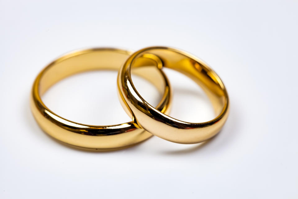Two intertwined gold wedding bands on a white background