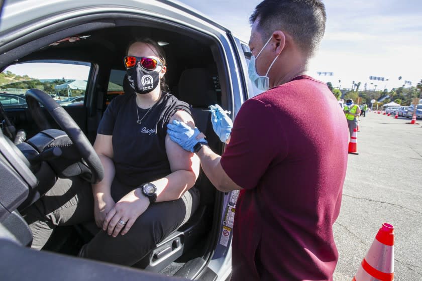 Los Angeles, CA - January 15: Dr. Richard Dang, right, Assistant professor USC School of Pharmacy administers COVID-19 vaccine to Ashley Van Dyke as mass-vaccination of healthcare workers takes place at Dodger Stadium on Friday, Jan. 15, 2021 in Los Angeles, CA. (Irfan Khan / Los Angeles Times)