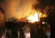 A police officer and rescue workers arrive at the site of bomb blast in Quetta, Pakistan, Wednesday, April 21, 2021. A powerful bomb went off in the parking area of a five-star Serena hotel in the southwestern city of Quetta on Wednesday, wounding some people, police said. (AP Photo/Arshad Butt)