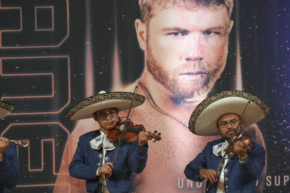 Mariachi musicians perform at the weigh-in ceremony for boxers Saul "Canelo" Alvarez of Mexico, in photo behind, and John Ryder of Britain, in Guadalajara, Mexico, Friday, May 5, 2023. Alvarez and Ryder will meet for a super middleweight championship fight at Akron Stadium on May 6. (AP Photo/Refugio Ruiz)