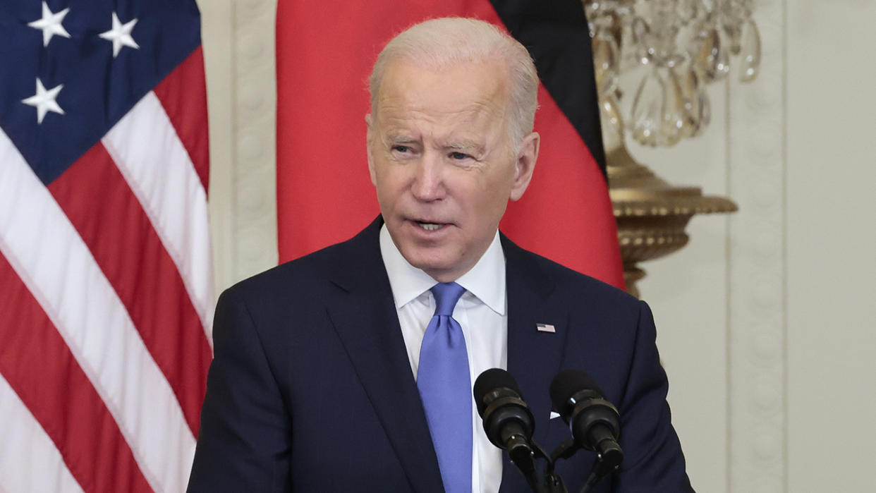 President Biden stands at a microphone as he delivers remarks during a joint news conference with German Chancellor Olaf Scholz. 