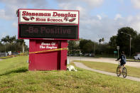 <p>A bicyclist rides past a sign at Marjory Stoneman Douglas High School on Friday, Feb. 23, 2018 in Parkland, Fla. Teachers and administrators returned for the first time since the Valentine’s Day shooting that killed several people. (Photo: Mike Stocker/South Florida Sun-Sentinel via AP) </p>