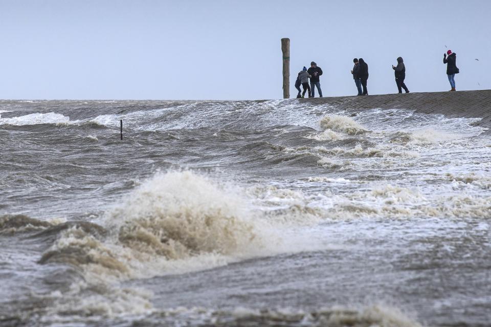 People watch the stormy sea in Harlesiel, Germany, Thursday, Oct. 21, 2021. Germany is hit by heavy rain and storms. (Sina Schuldt/dpa via AP)